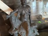 une statue représentant une femme assise sur un rocher, un livre à la main