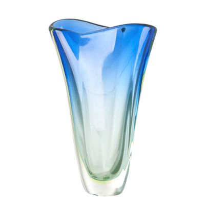 un vase en verre bleu et vert posé sur une surface blanche