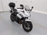 une moto blanche garée dans une pièce aux murs blancs
