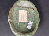 a green vase with a tag on it sitting on a table
