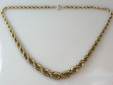 gros plan d'un collier en or sur une surface blanche