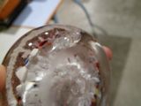 une personne tenant un verre rempli de glaçons et de confettis