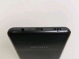 the back of a black samsung phone sitting on top of a white table
