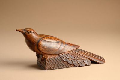 carved wooden bird sitting on top of a piece of wood