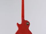 a red electric guitar hanging from a string on a white wall