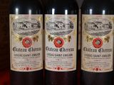 three bottles of red wine are lined up on a table