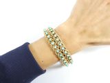 gold and turquoise beaded bracelet on a woman ' s hand