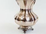 a silver vase that is sitting on a white surface