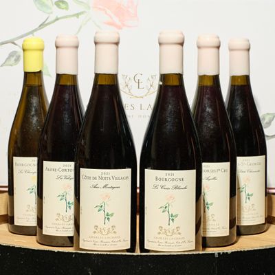 six bottles of wine are lined up on a wooden tray