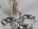 a silver cocktail shaker and other silverware on a table