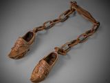 a pair of shoes hanging from a chain on a gray surface