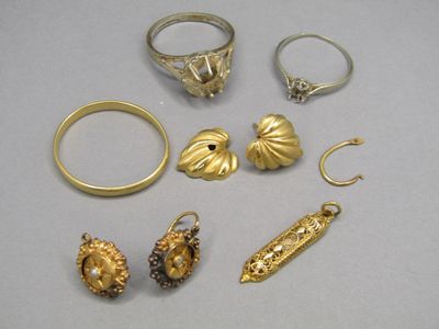 quelques bagues en or et d'autres bijoux posés sur une surface blanche