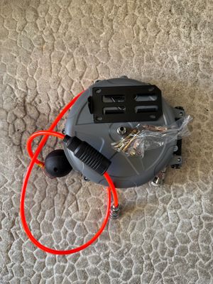 un aspirateur posé par terre, muni d'un cordon rouge