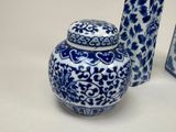 a blue and white vase with a lid next to a blue and white vase