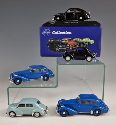 three toy cars are on display in front of a blue box