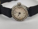 an image of a woman ' s wrist watch on a black leather strap