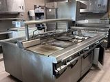 une grande cuisine professionnelle équipée d'appareils électroménagers et de plans de travail en acier inoxydable