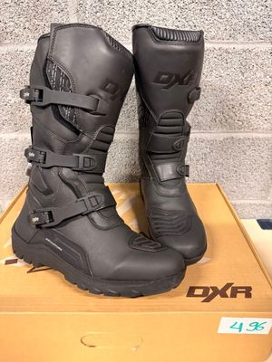 black motorcycle boots with buckles on top of a cardboard box