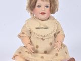 a doll that is sitting on the ground wearing a dress and hat