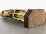 a wooden bench with a doll laying on top of it