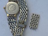 a silver watch and a silver bracelet on a white surface