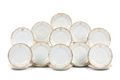 une pile d'assiettes blanches et dorées posées sur une surface blanche