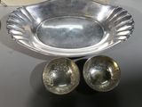 a silver bowl and two silver spoons on a table