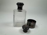 une petite bouteille en verre et une petite tasse en métal