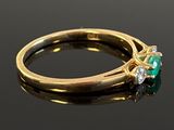 an emerald and diamond ring on a black surface