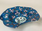 a blue bowl with flowers on it sitting on a table