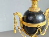 a black and gold vase sitting on a white pedestal