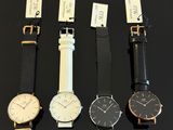 four different styles of watches are displayed on a black surface
