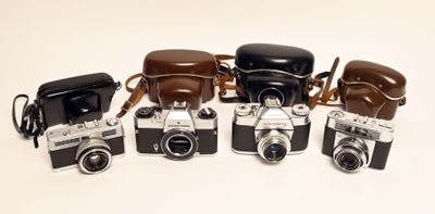 cinq vieux appareils photo alignés en rang sur une surface blanche