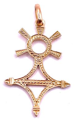 a close up of a gold pendant with a cross on it