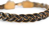 a close up of a black and gold bracelet on a white background