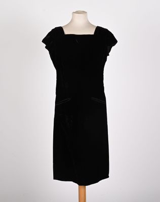 a black dress on a mannequin stand with a white background