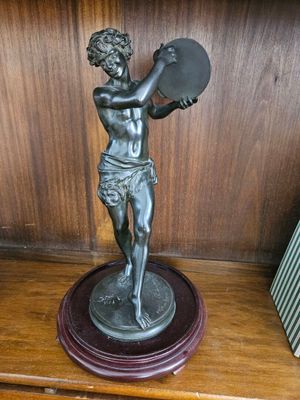 une statue représentant un garçon tenant un éventail, posée sur une étagère