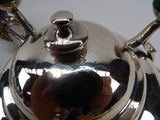 someone is taking a picture of a silver tea pot on a table