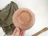 a person holding a clay bowl with a wooden handle