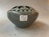 a green vase with holes in it sitting on a table