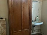 a wooden cabinet in the corner of a bathroom