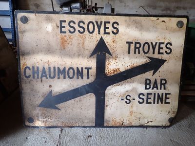 un panneau rouillé sur lequel figurent des flèches pointant dans différentes directions