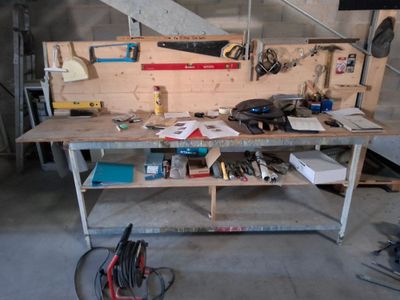 un établi dans un garage, sur lequel sont posés de nombreux outils