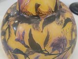 a yellow vase with birds on it sitting on a table
