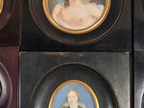 four framed portraits of women in black and gold frames on a white wall