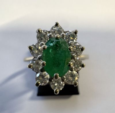 gros plan d'une bague avec une pierre verte entourée de diamants blancs
