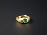 gros plan d'une bague en or avec une pierre verte