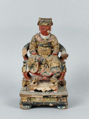 an old statue of a man sitting on a chair with a cat