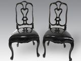 une paire de chaises peintes en noir, avec des assises recouvertes de cuir noir