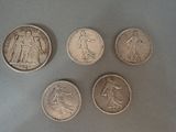 four different types of silver coins on a gray surface